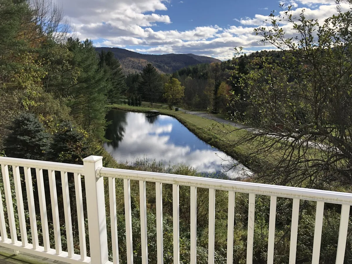 A serene landscape featuring a pond, rolling mountains in the distance, and trees under a cloudy sky. The setting is peaceful and ideal for outdoor activities such as hiking, fishing, picnicking, or simply relaxing and admiring the views—perfectly capturing the spirit of outdoor adventure.