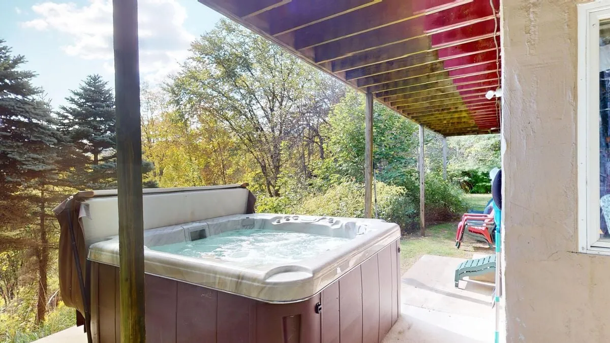 This image captures a tranquil outdoor setting with a bubbling hot tub as the focal point. The surrounding greenery and patio area create a peaceful, inviting atmosphere, ideal for relaxation and connection with nature. The scene is perfect for showcasing stargazing, morning coffee, or socializing against a natural backdrop.