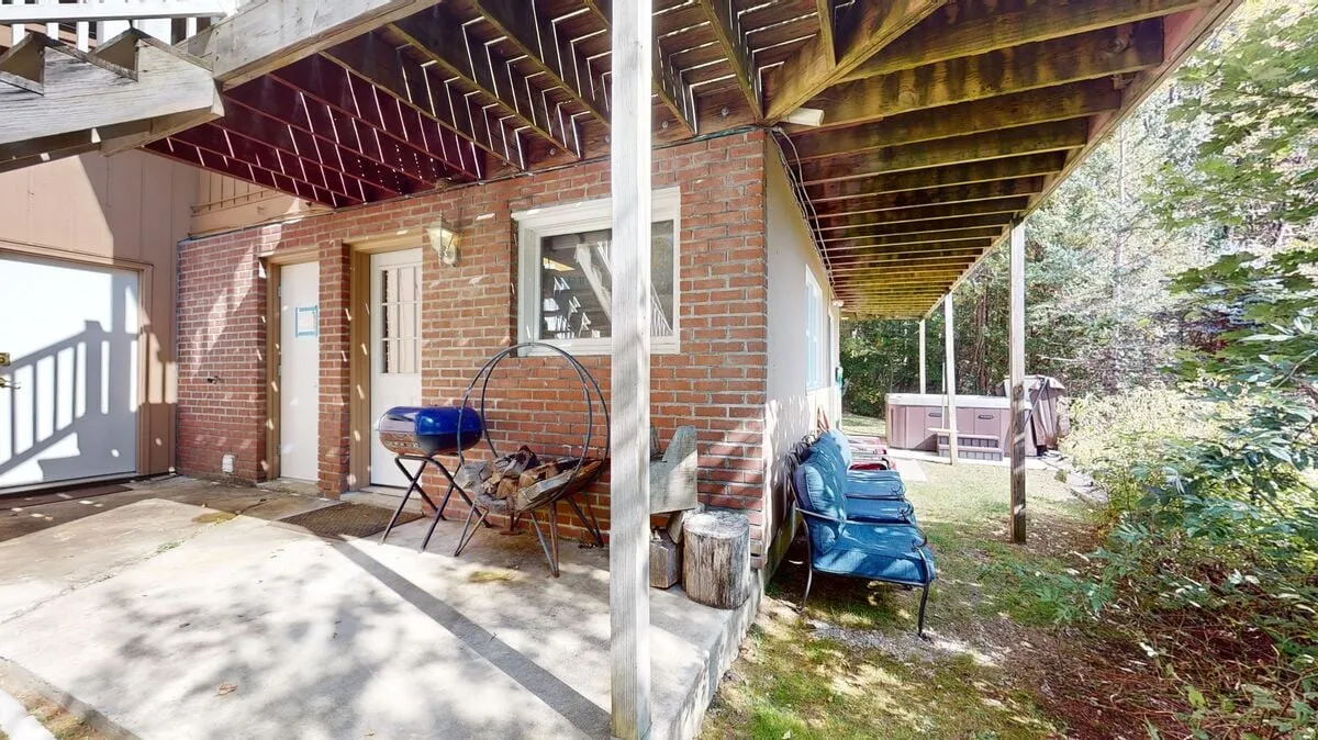 An outdoor space complete with a brick wall, casual seating, a grill, and a hot tub—set for relaxation and social gatherings. The area is designed for unwinding after an active day, with sunset views and space for family or team retreats under the stars.